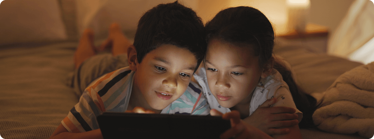 Two children watching a tablet together in a cozy room