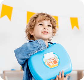 Smiling child holding a blue lunchbox